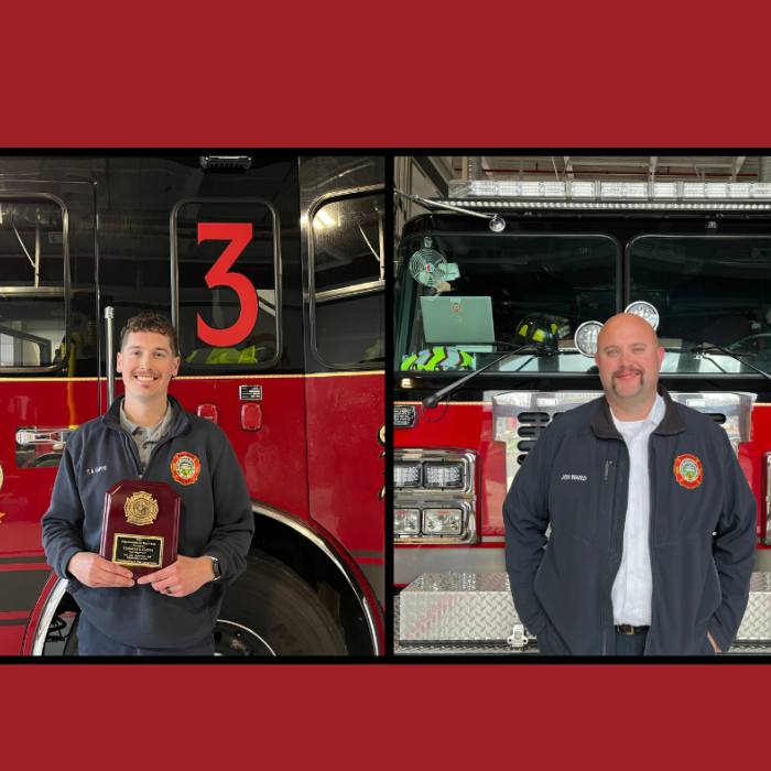 2 firefighters standing in front of a fire engine