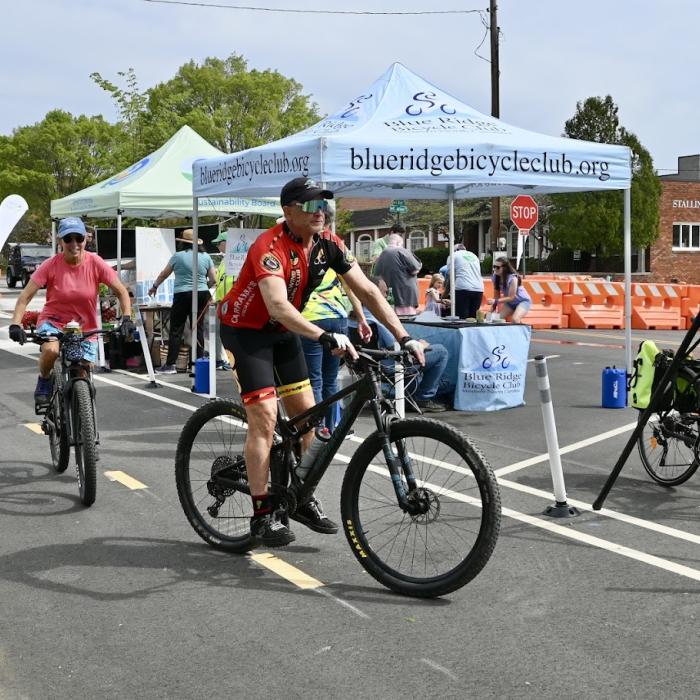 Bikes riding down Main Street, with event tents in the background at Hendo Earth Fest. 