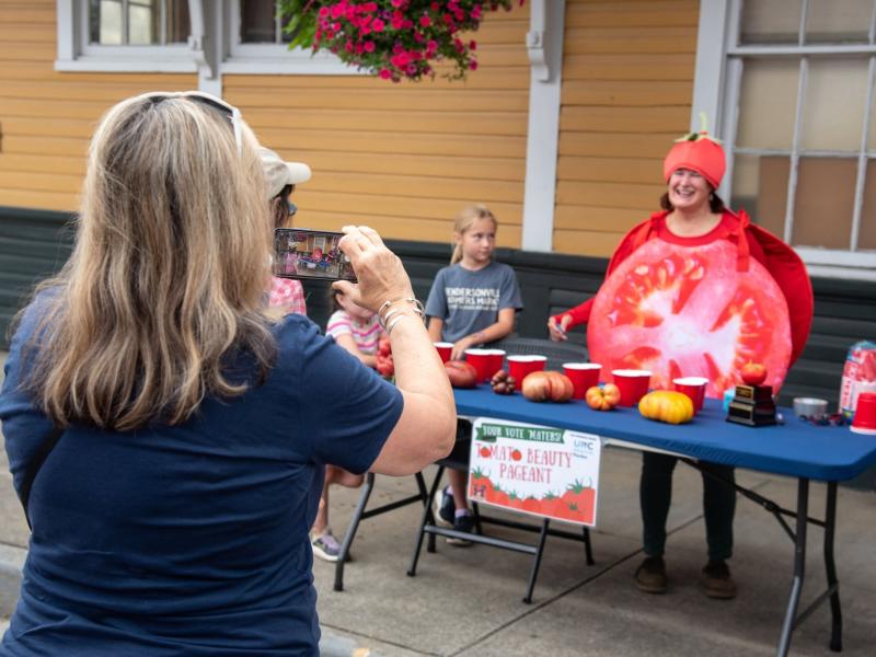 a customer taking a picture of Terrye Tomato at the tomato beauty pageant station