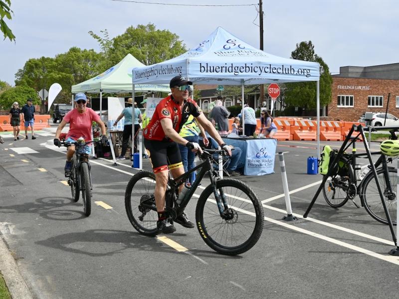 Bikes riding down Main Street, with event tents in the background at Hendo Earth Fest. 
