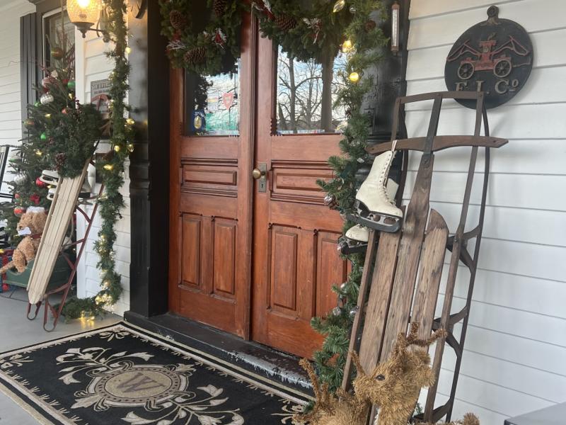 Entryway of a historic inn, decorated with garland, reindeer, and a wooden sleigh.