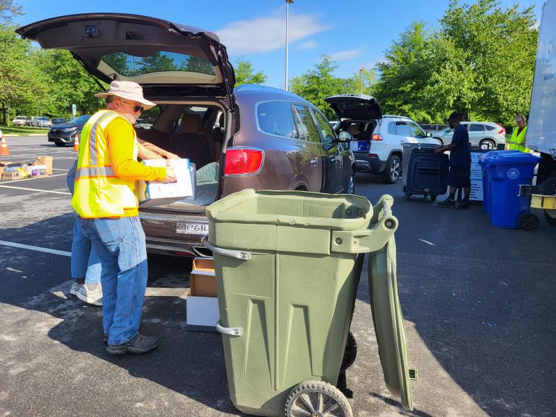 A person is dumping a box of documents into a trash can for shredding.