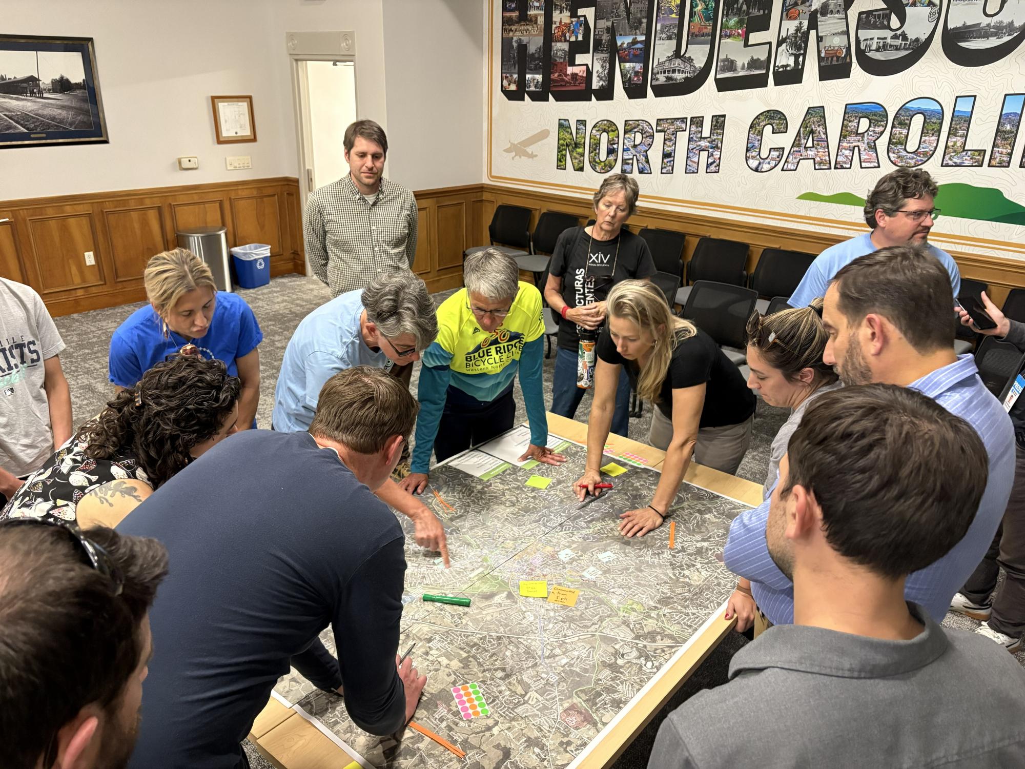 People gathered around and pointing at a map on a table