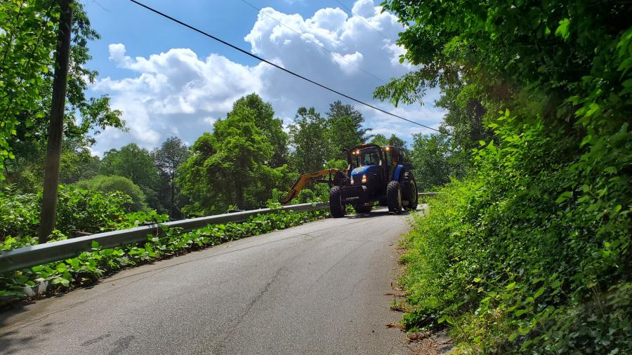 Side arm tractor cleaning up roadside vegetative debris