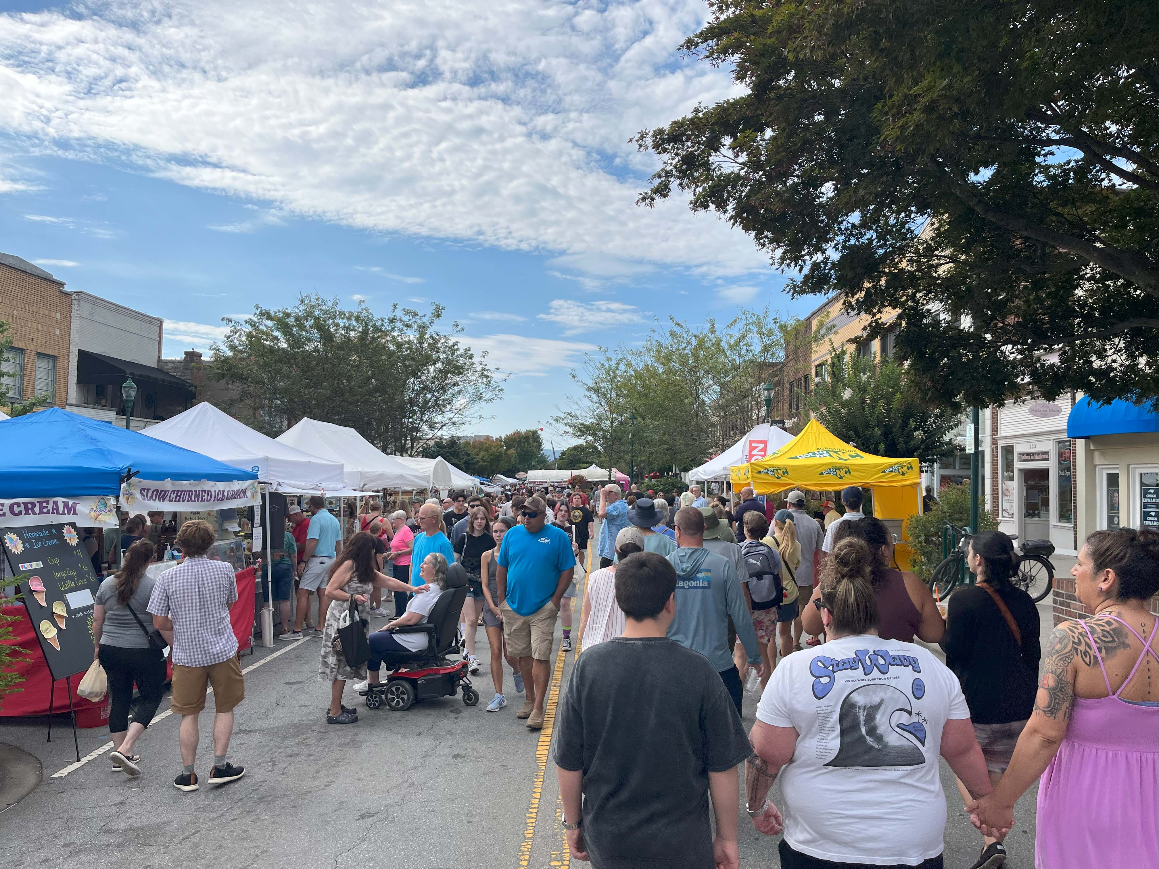 People walking outside on a sunny day during the apple festival.