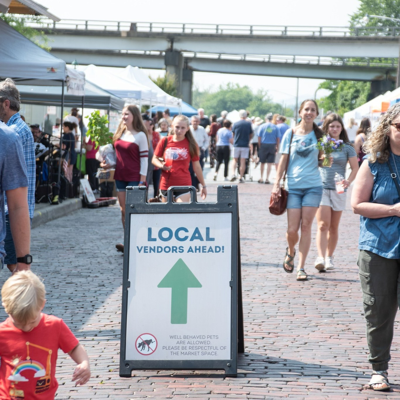 a picture of the Hendersonville Farmers market with a sign that points into the market saying local vendors ahead