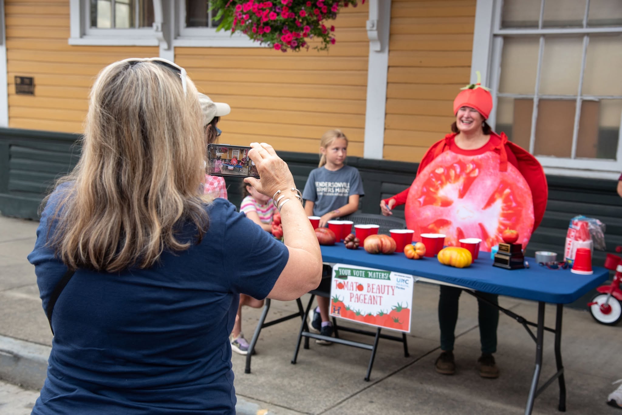 a customer taking a picture of Terrye Tomato at the tomato beauty pageant station