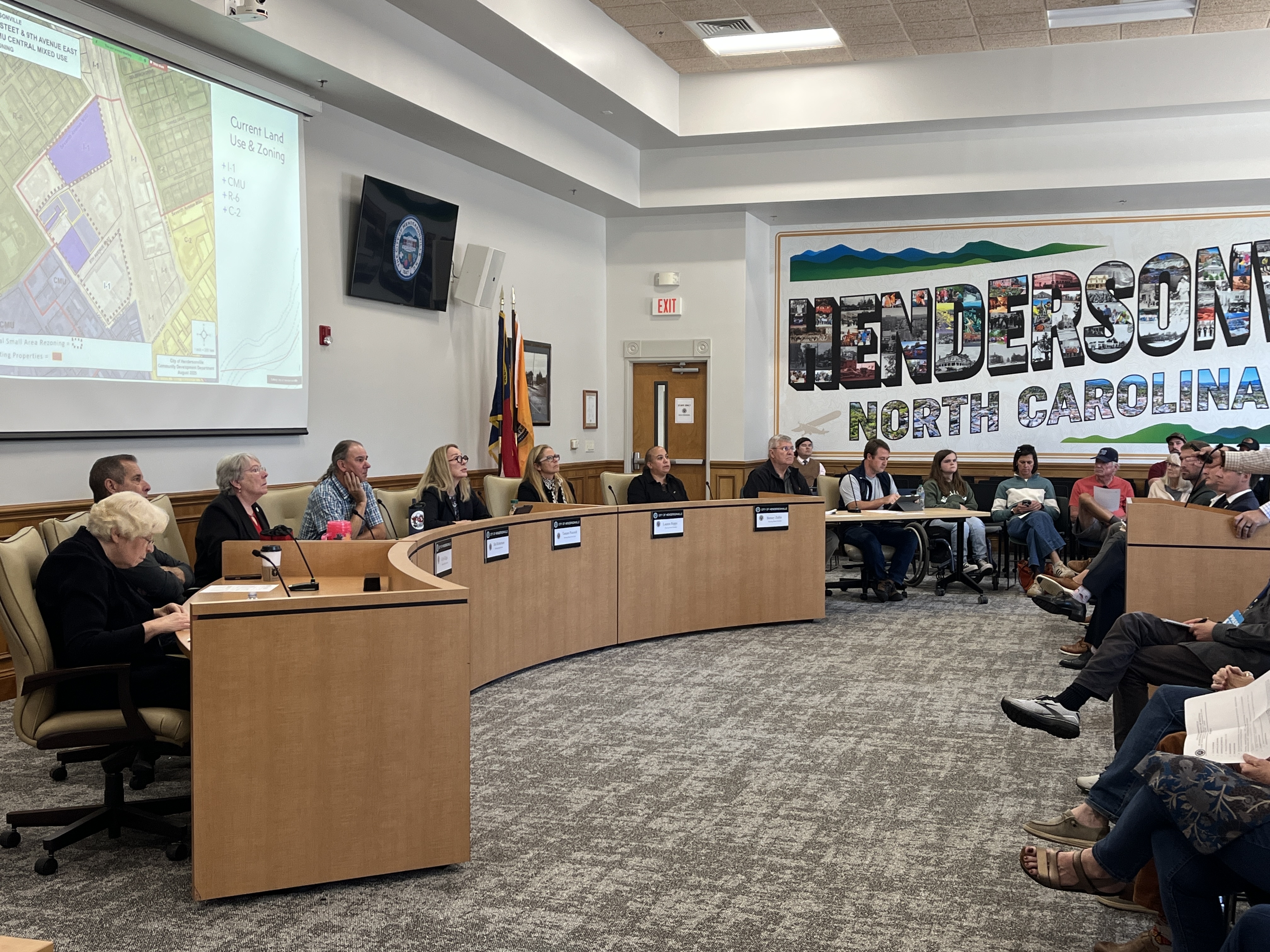 a group of individuals serving on an advisory board sit at a large dais. 
