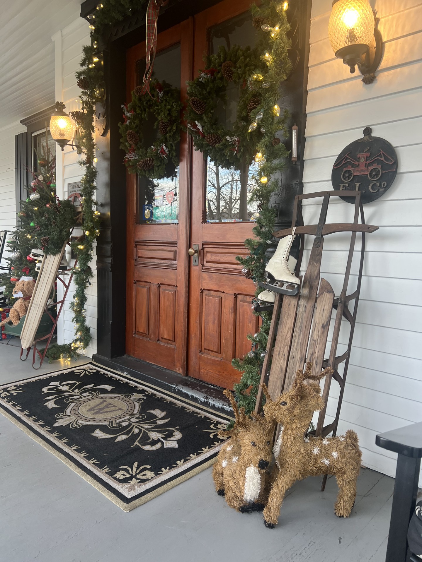Entryway of a historic inn, decorated with garland, reindeer, and a wooden sleigh.