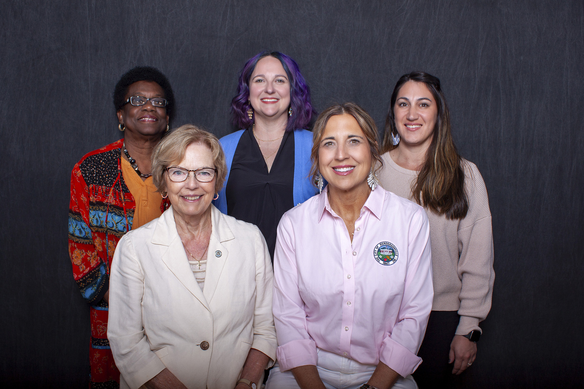 5 female council members smiling and standing on a sidewalk